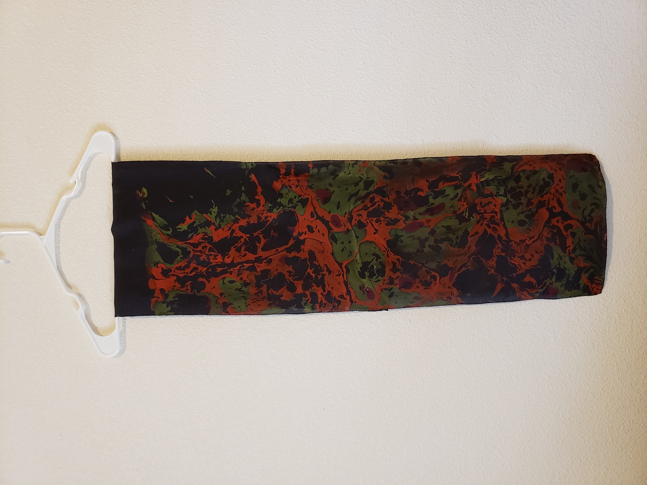 Marbled silk scarf hanging against a light wall